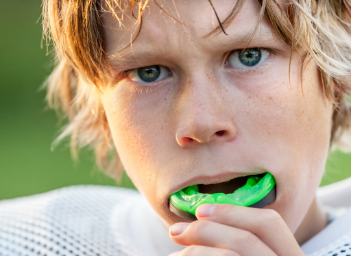boy putting in green sports mouth guard